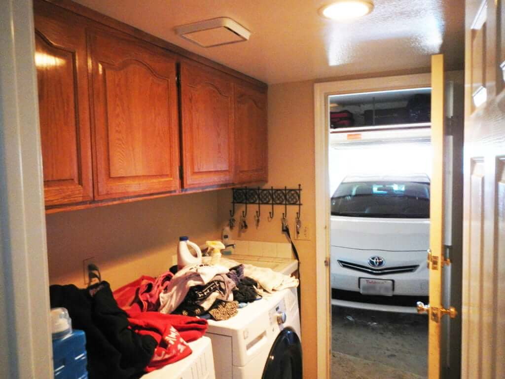 messy old laundry room with cabinets above and garage in background