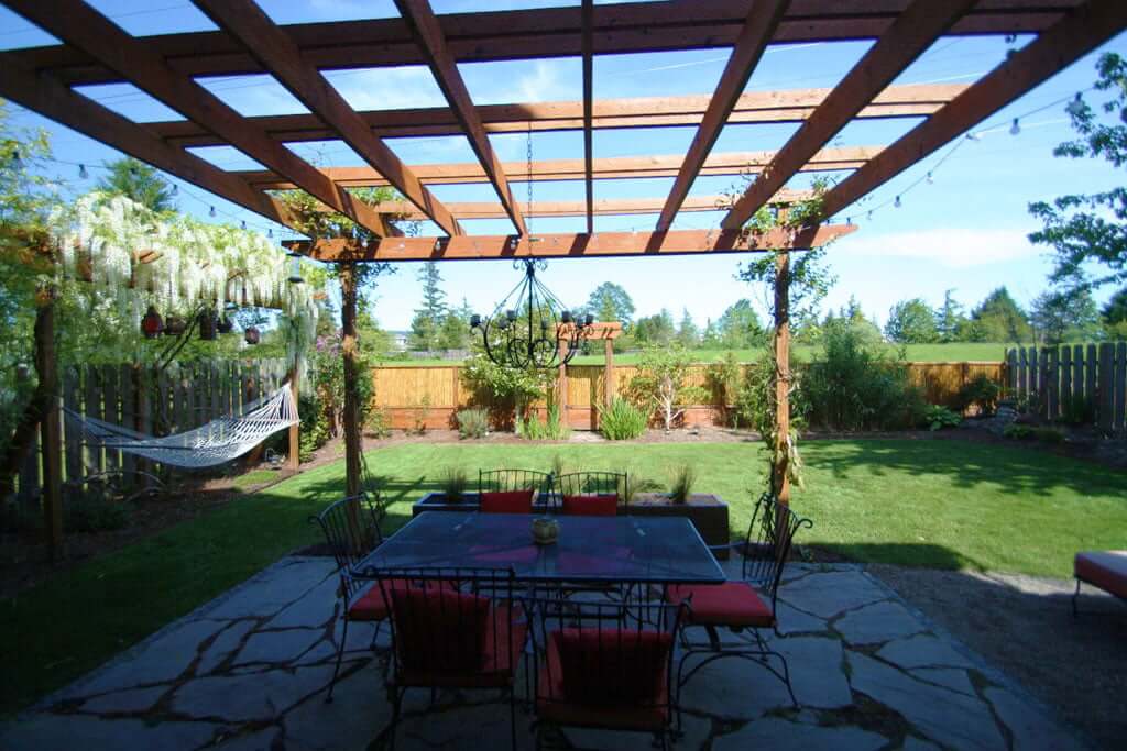 Backyard view of arbor dining set hammock under wisteria