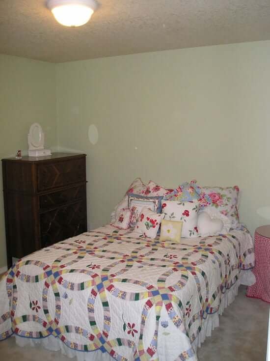 Bedroom with light green walls bed and chest of drawers