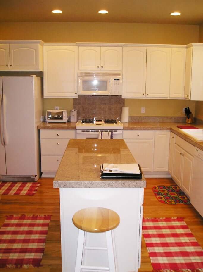 Kitchen before with white cabinets granite countertops and yellow walls