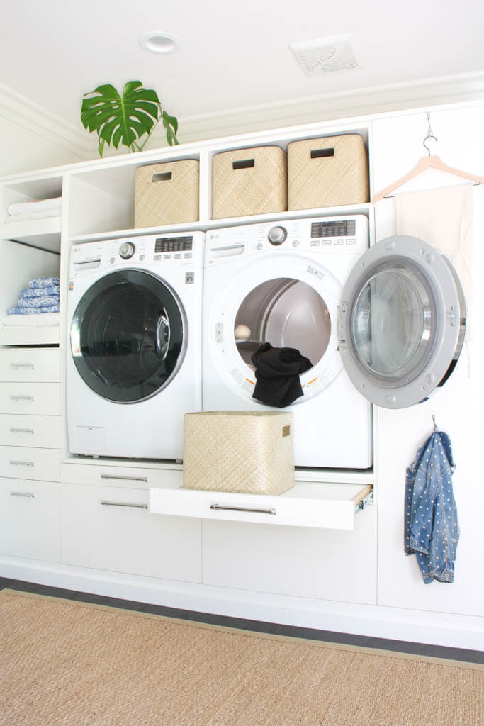 Built in laundry room shelf that holds washer and dryer and has storage for shelves and baskets. 