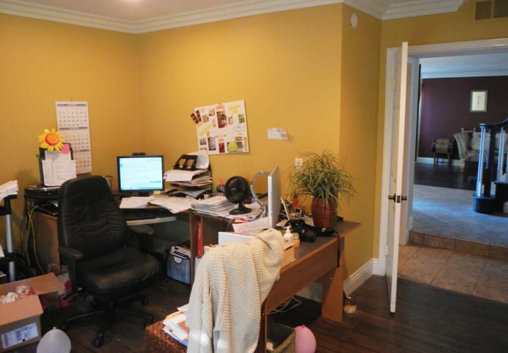 messy office with papers all over desk and yellow walls