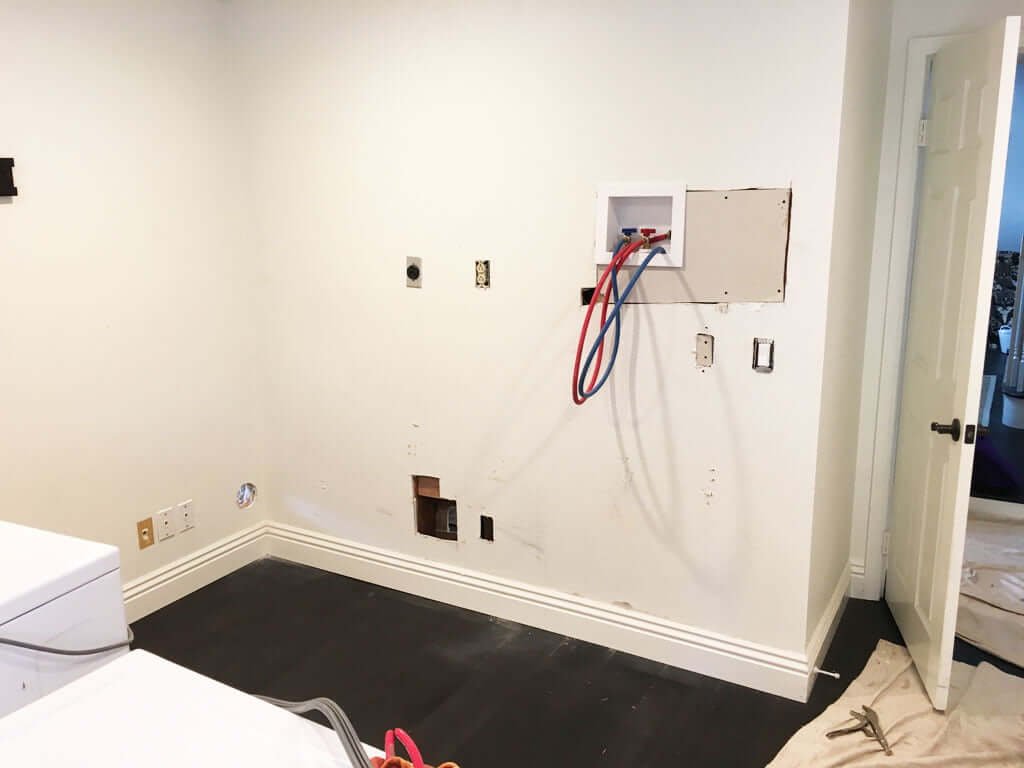 blank wall with hot and cold water lines showing, hole in corner for dryer vent