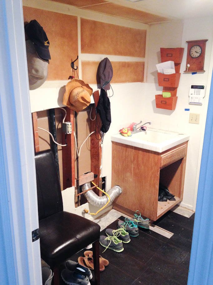 mudroom in progress, testing phase with chair, shoes on floor, hooks on wall, sink in corner