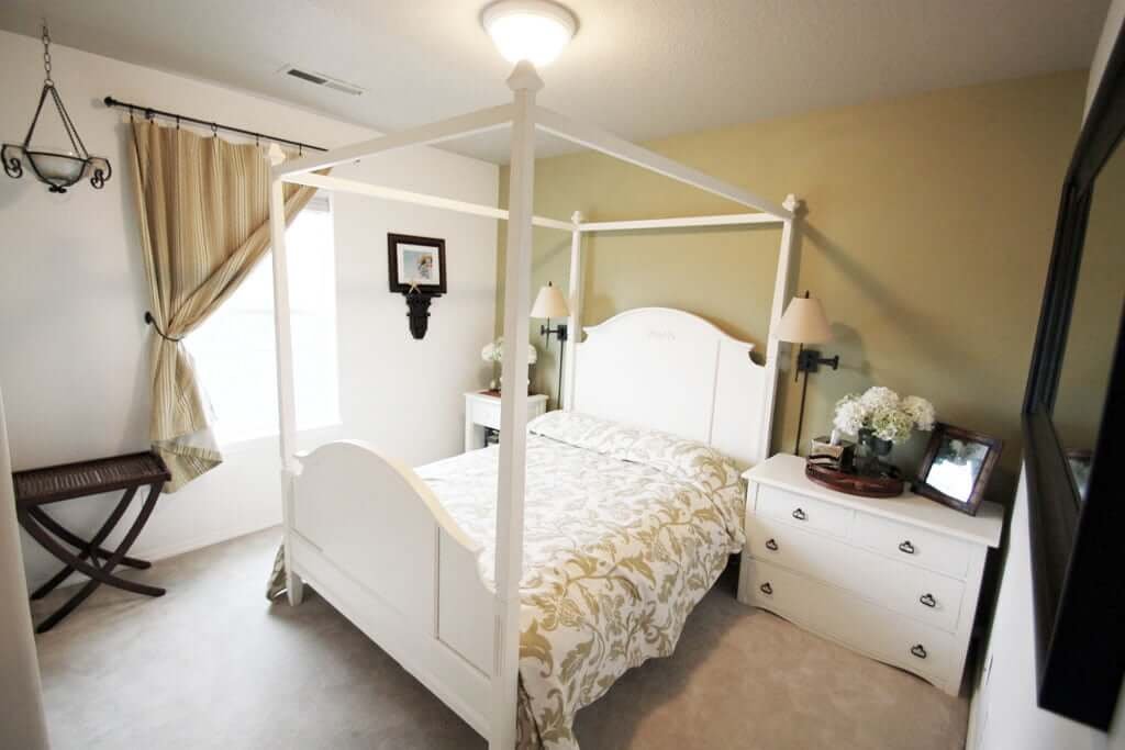 Bedroom with canopy bed white walls and green accent wall