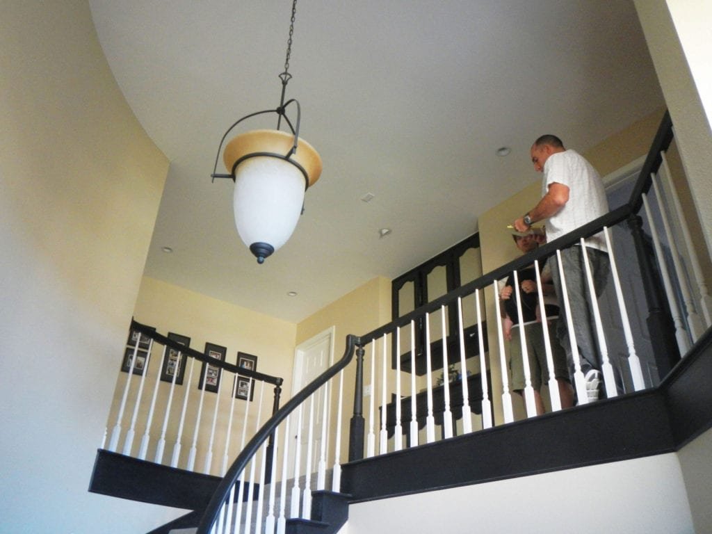 looking up from entryway to stairway landing on second floor with chandelier