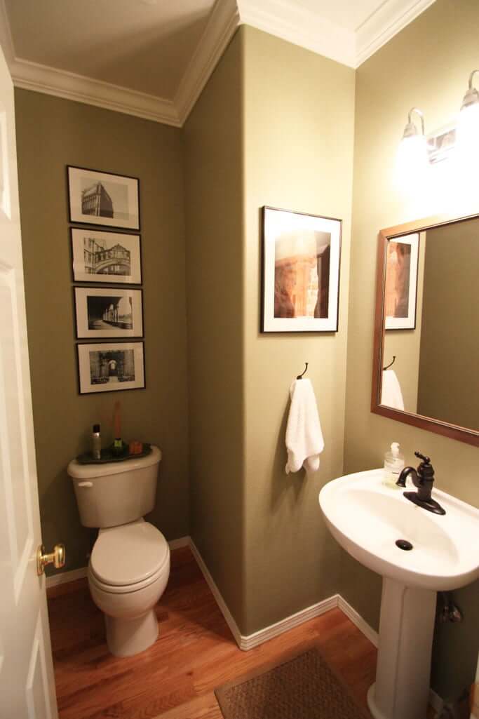 Powder bath with olive green walls and framed photos and bronze faucet