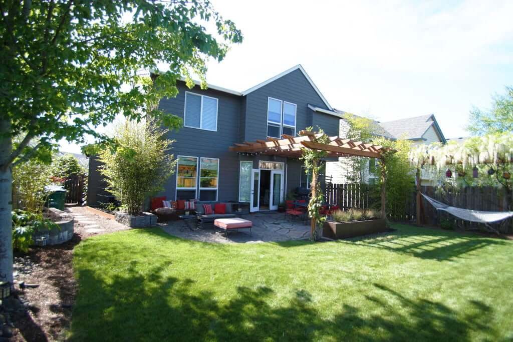 Back of house view showing sideyard, arbor seating areas and bamboo planters, hammock and wisteria growing over arbor