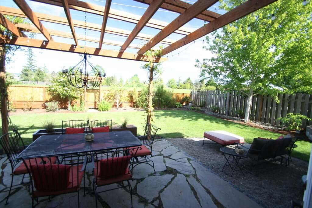 backyard view with dining set arbor firepit, lawn and bamboo fence