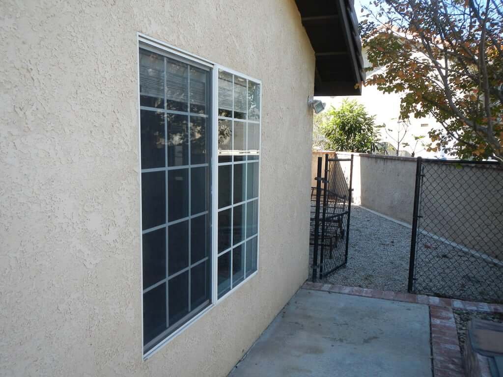 side of house with window and dog run in distance