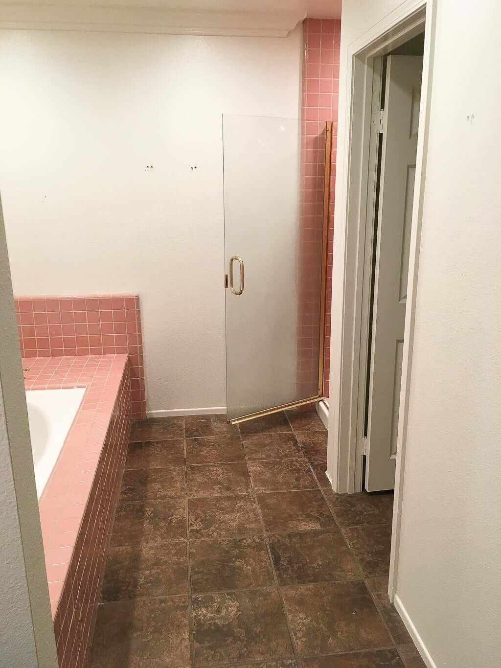 bathroom remodel before pic with pink tile tub, shower, and brown tile floor