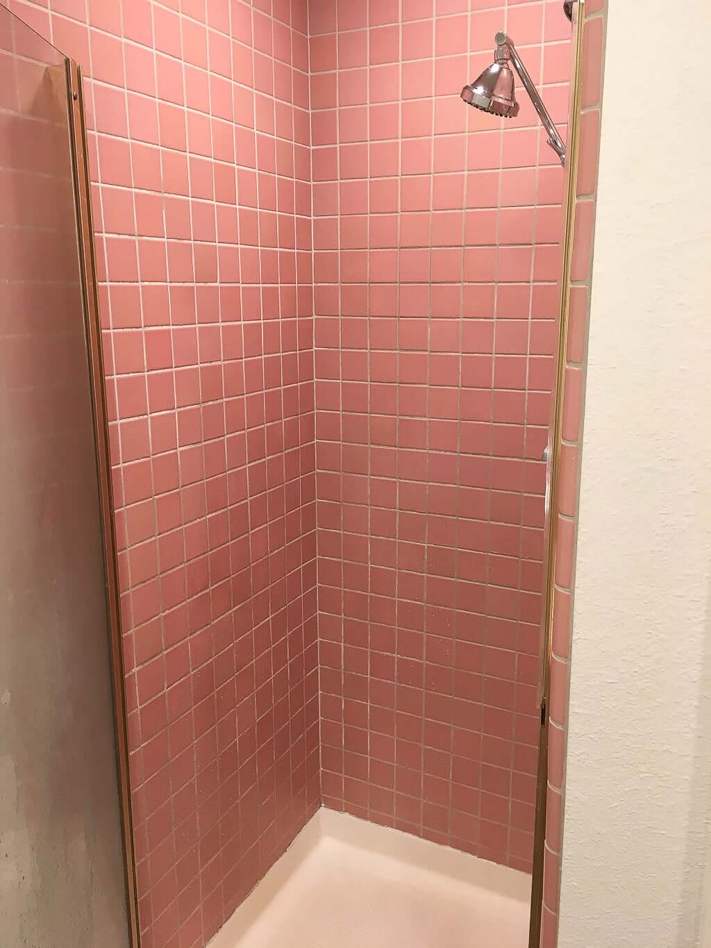 narrow bathroom shower with showerhead and pink tile