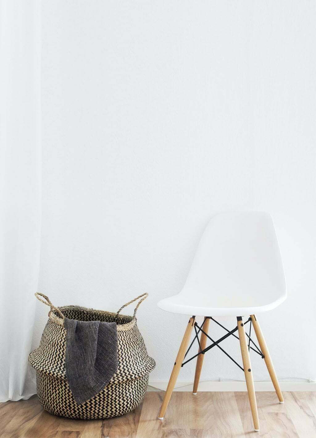 blank wall with chair and basket in foreground
