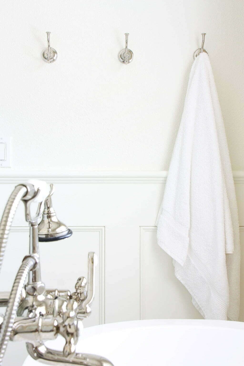 polished nickel hooks on wall with polished nickel freestanding tub hardware in foreground