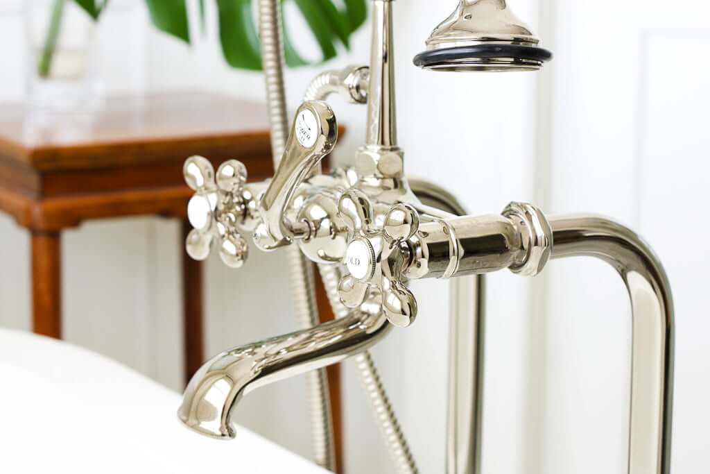 closeup of polished nickel freestanding tub hardware with cross handles for hot and cold