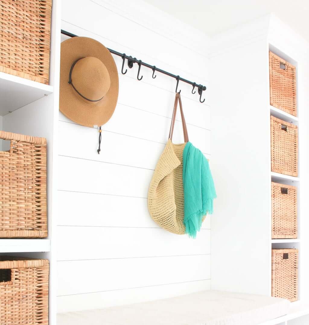 White DIY mudroom storage entryway bench with cushion and storage baskets in mudroom cubbies, with wall hooks