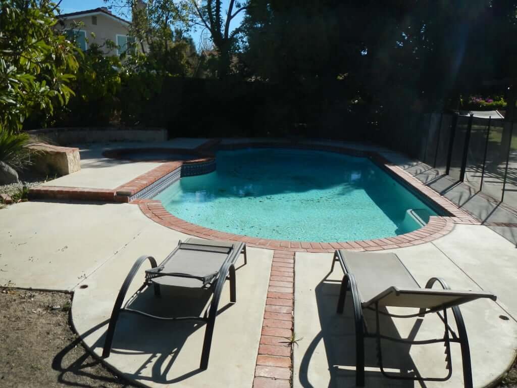 pool with brick and concrete and two chaises pointed towards it