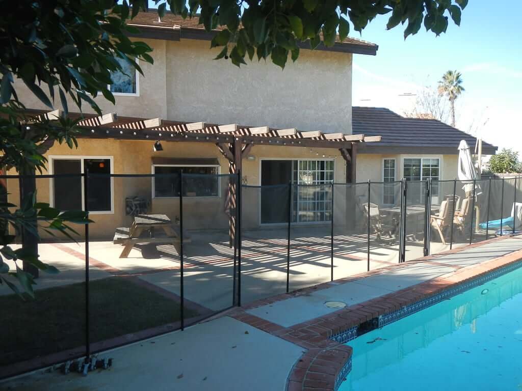 back of house with pergola, pool fence, and pool in foreground