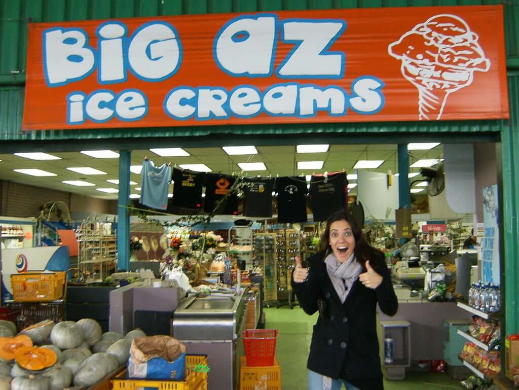 woman giving thumbs up in front of new zealand ice cream sign