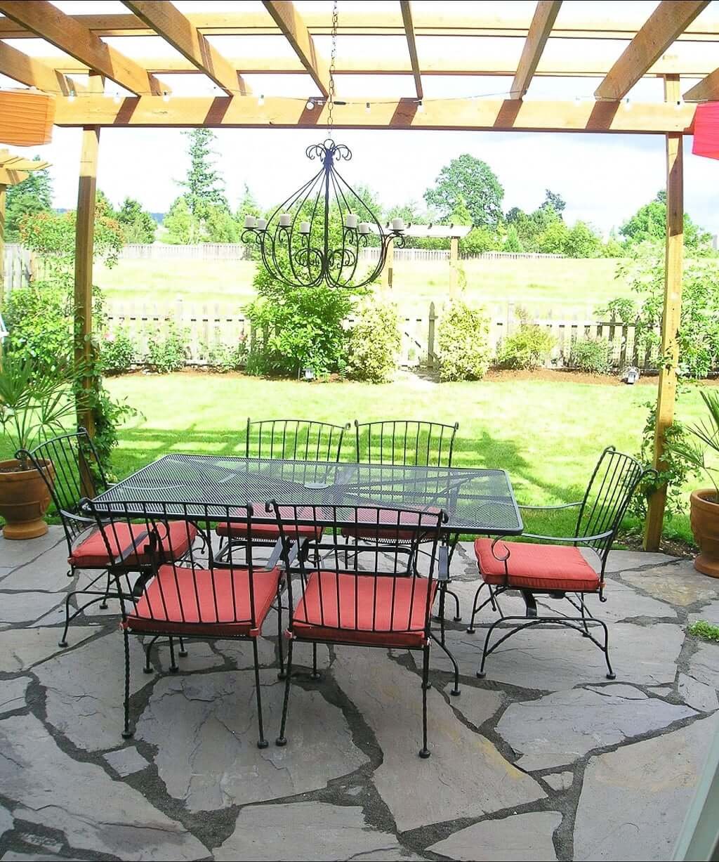 outdoor dining table and chairs with pergola above, flagstone patio and lawn