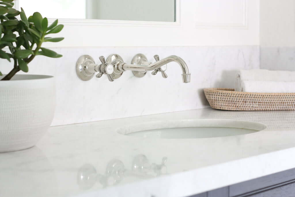 polished nickel wall-mount faucet in master bathroom double vanity with marble countertop