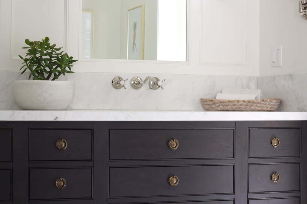 double sink bathroom vanity, wood with marble counter top and brass ring pulls, wall-mounted faucet and wall sconces