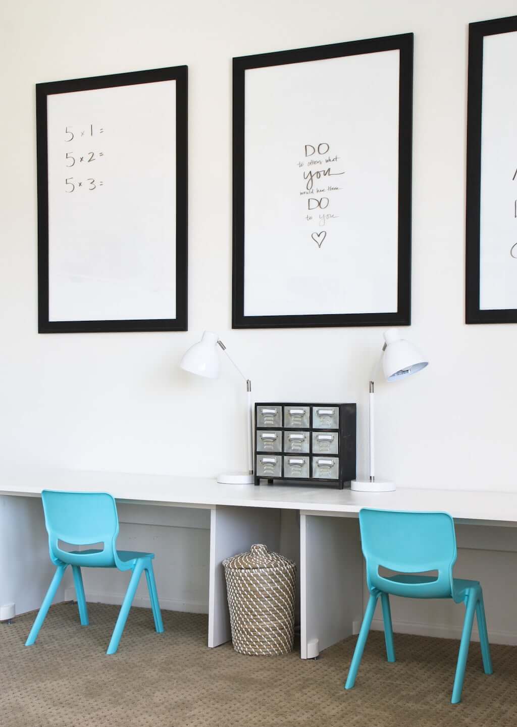 three dry erase frames above double children's IKEA desk in minimalist homeschool room with chairs and lamps