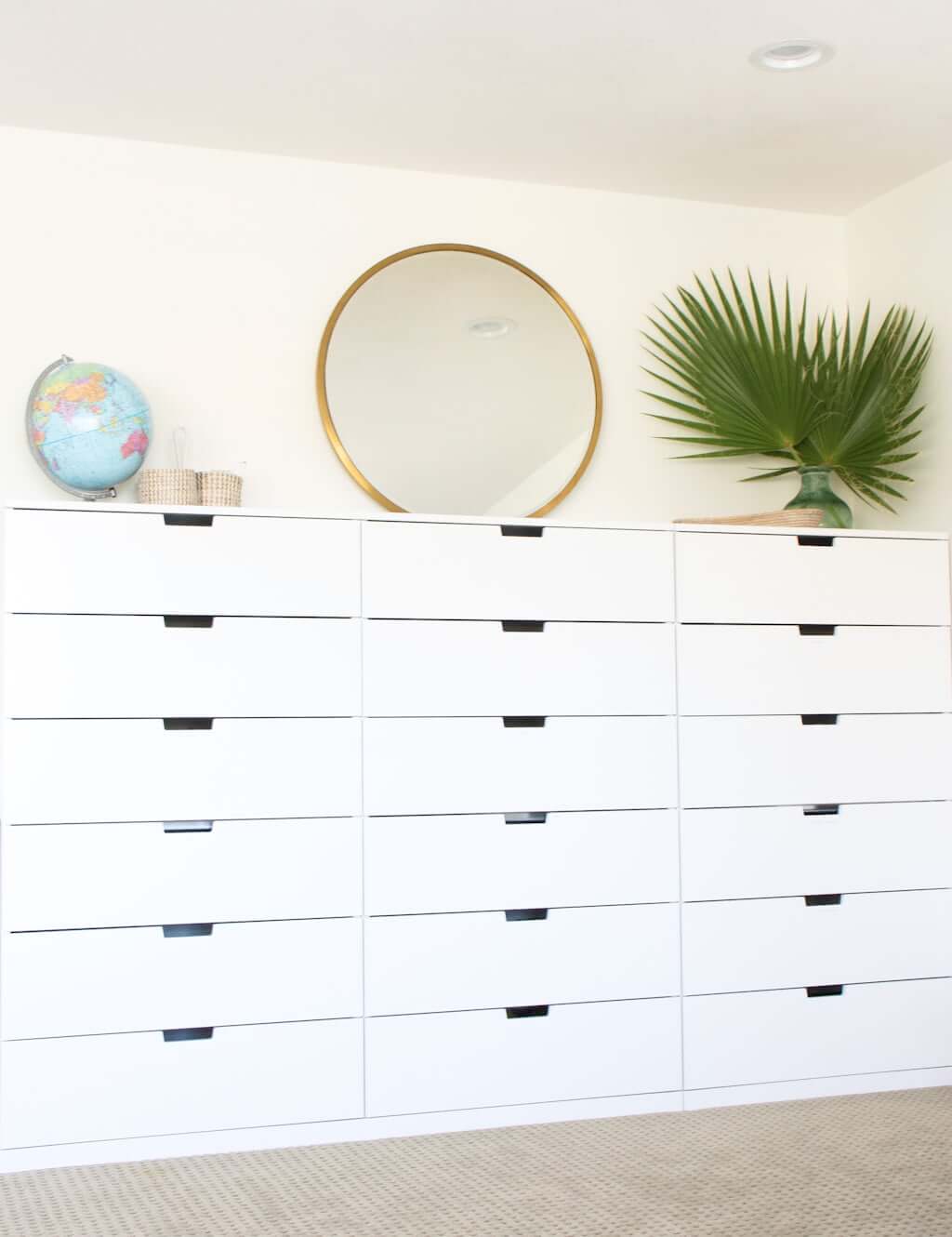 IKEA homeschool drawer storage on wall with mirror, globe, and fan palm in vase