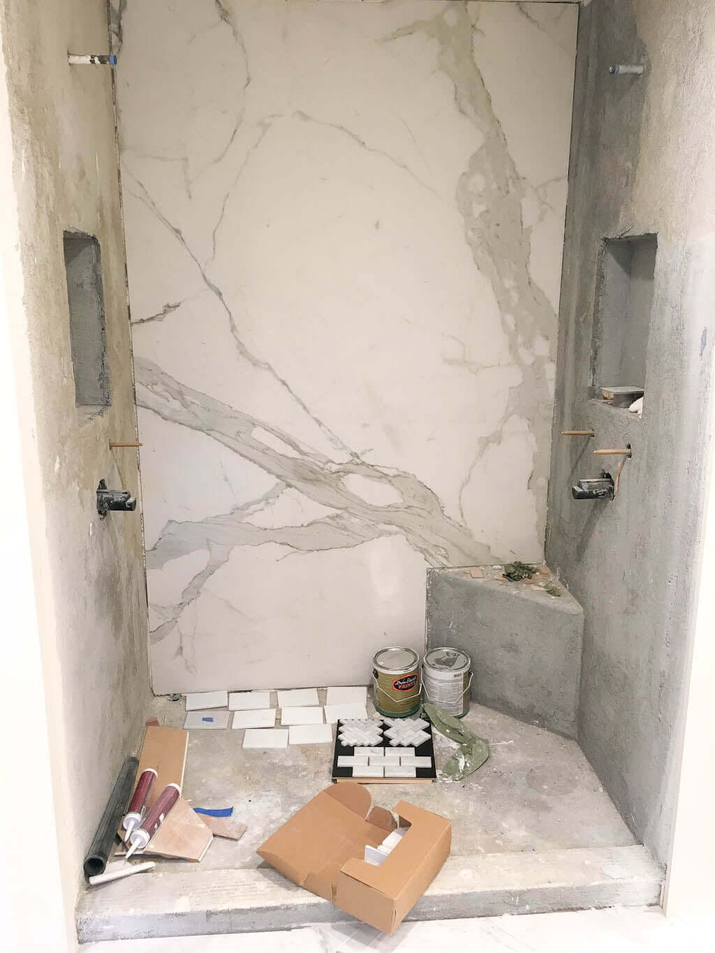 unfinished shower floor tile with various marble floor tiles laid on ground