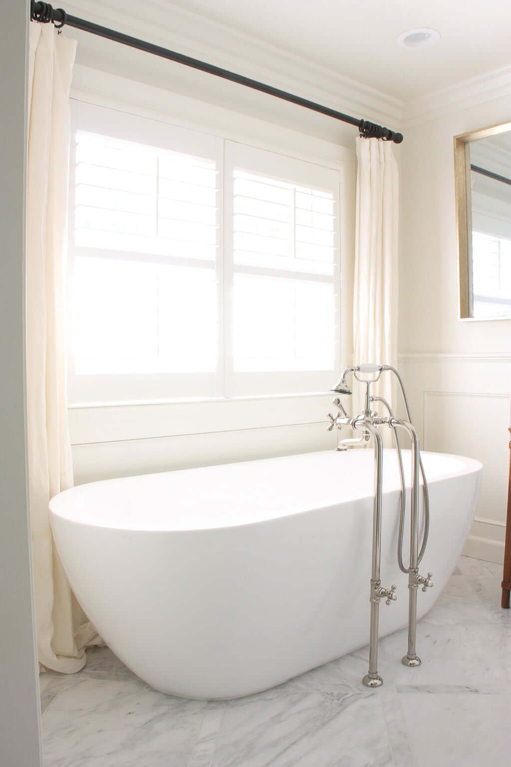 freestanding tub in bathroom with marble floors