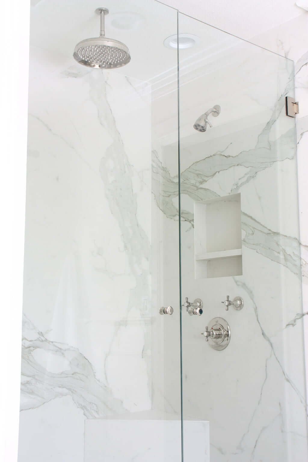 marble shower with double shower heads, rain shower head and niches