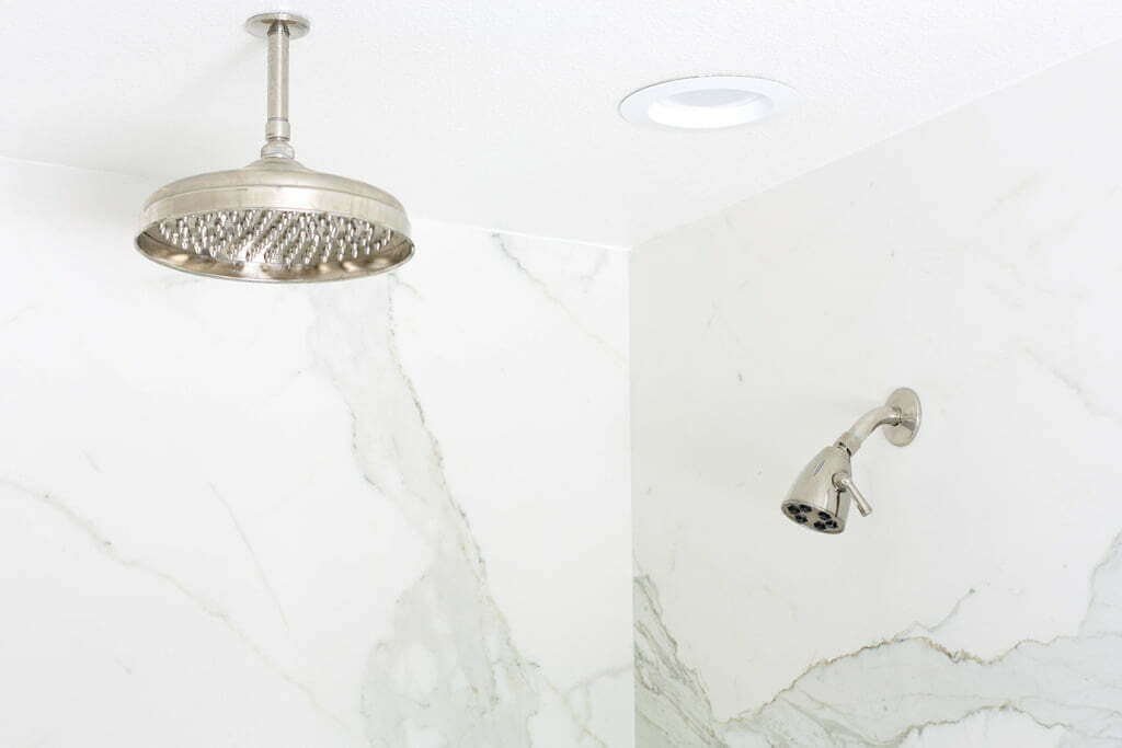 polished nickel rain shower head and regular shower head in marble shower