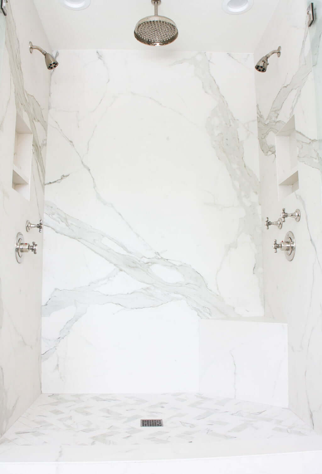 marble double walk-in shower with herringbone floor tile