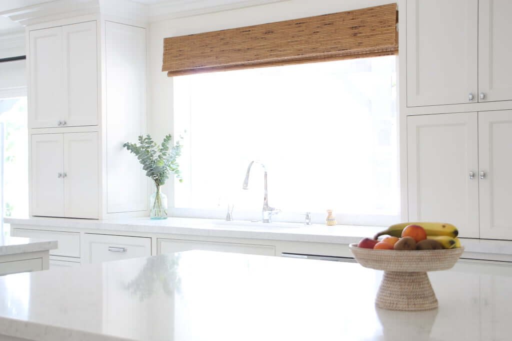 white kitchen, looking across kitchen island countertop to sink and window