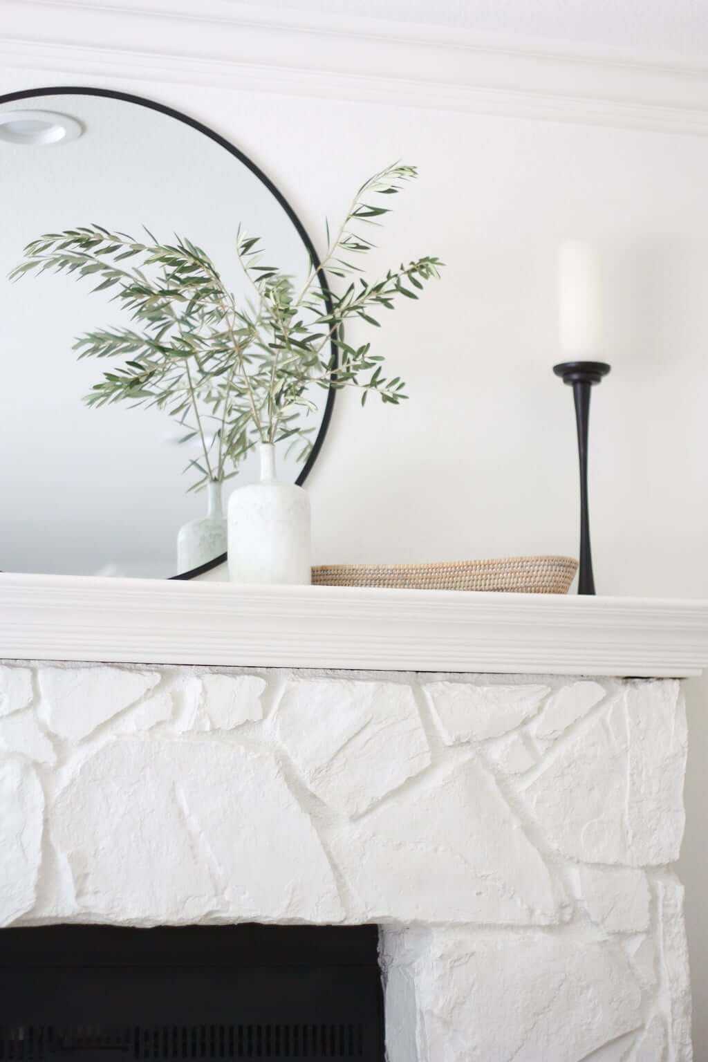 stone fireplace painted white with white mantel and neutral decor