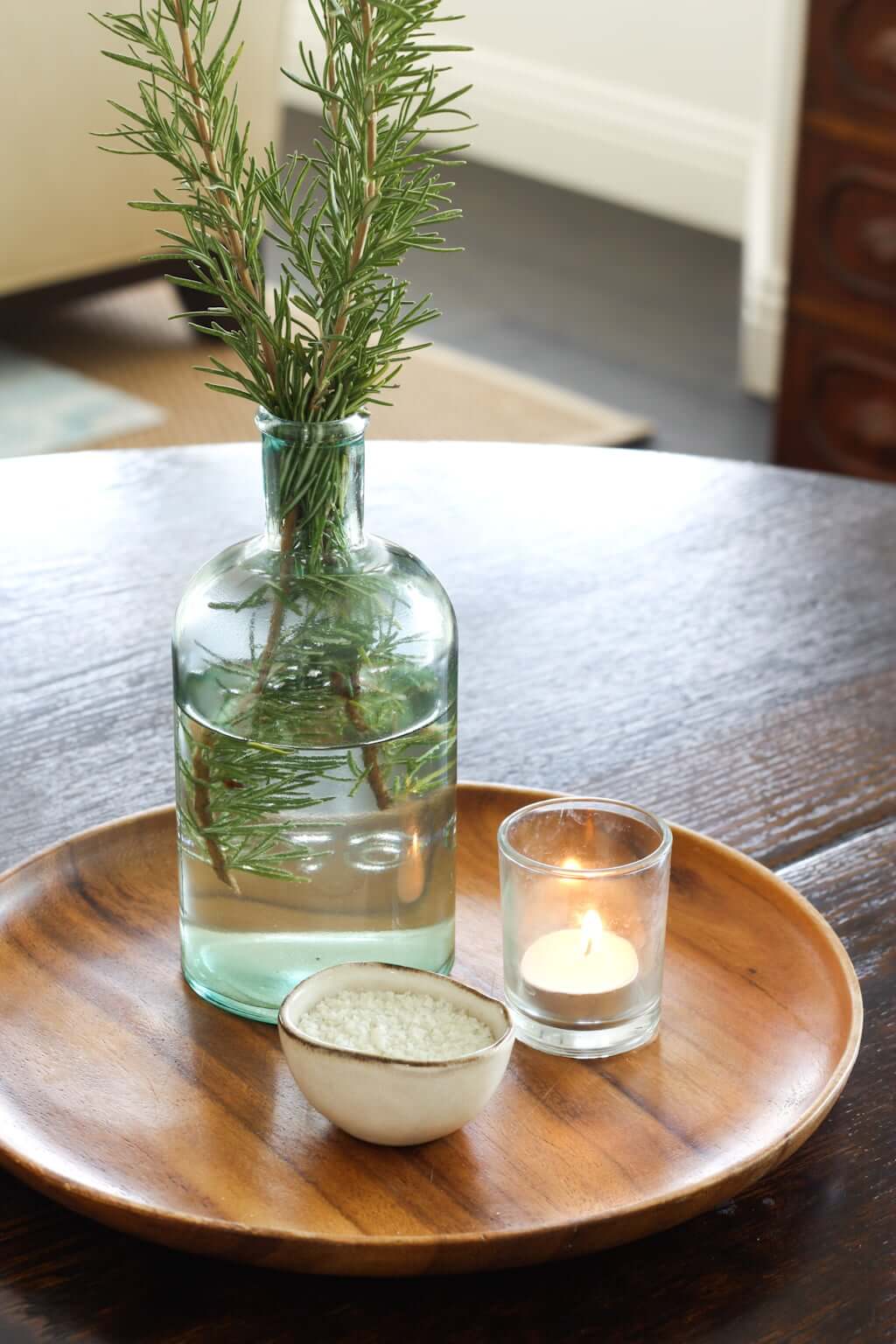 wood plate centerpiece with rosemary in glass vase, candle, and salt bowl