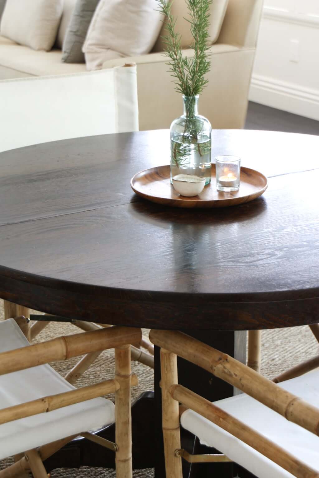 round dining table, dark wood, with a centerpiece of rosemary in vase