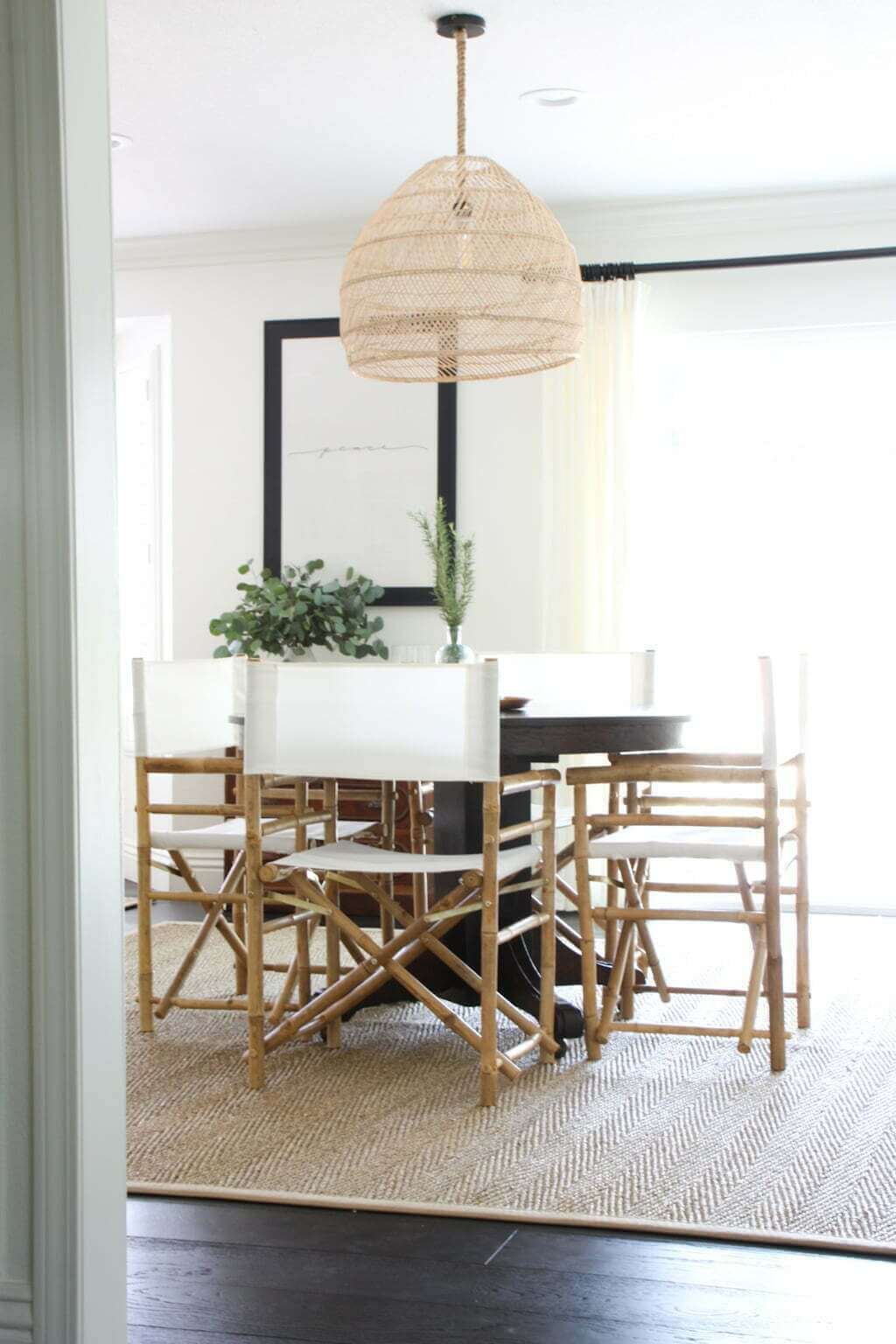 small dining room table with director's chairs and woven chandelier on seagrass rug