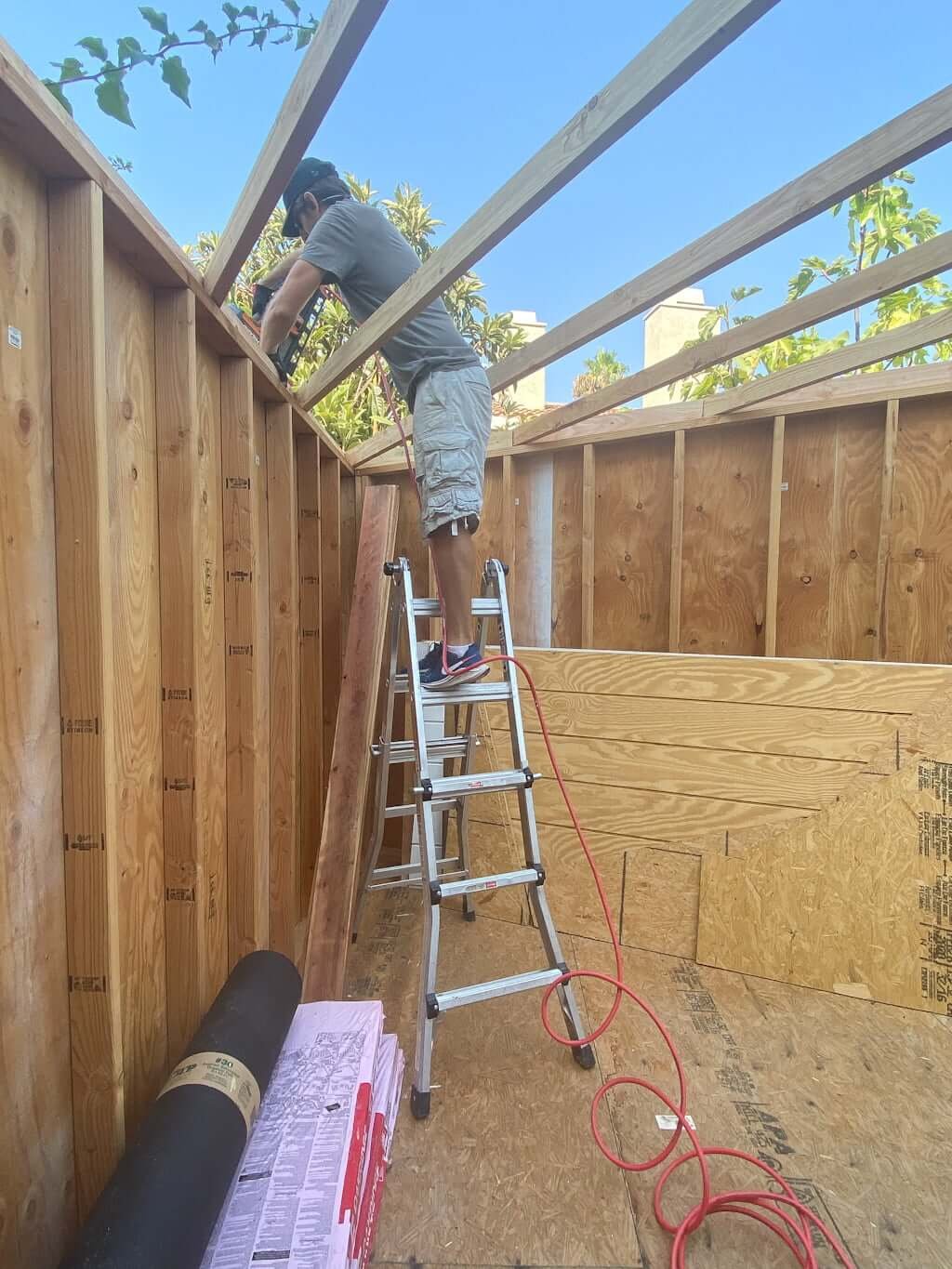 man working on roof while building art studio shed