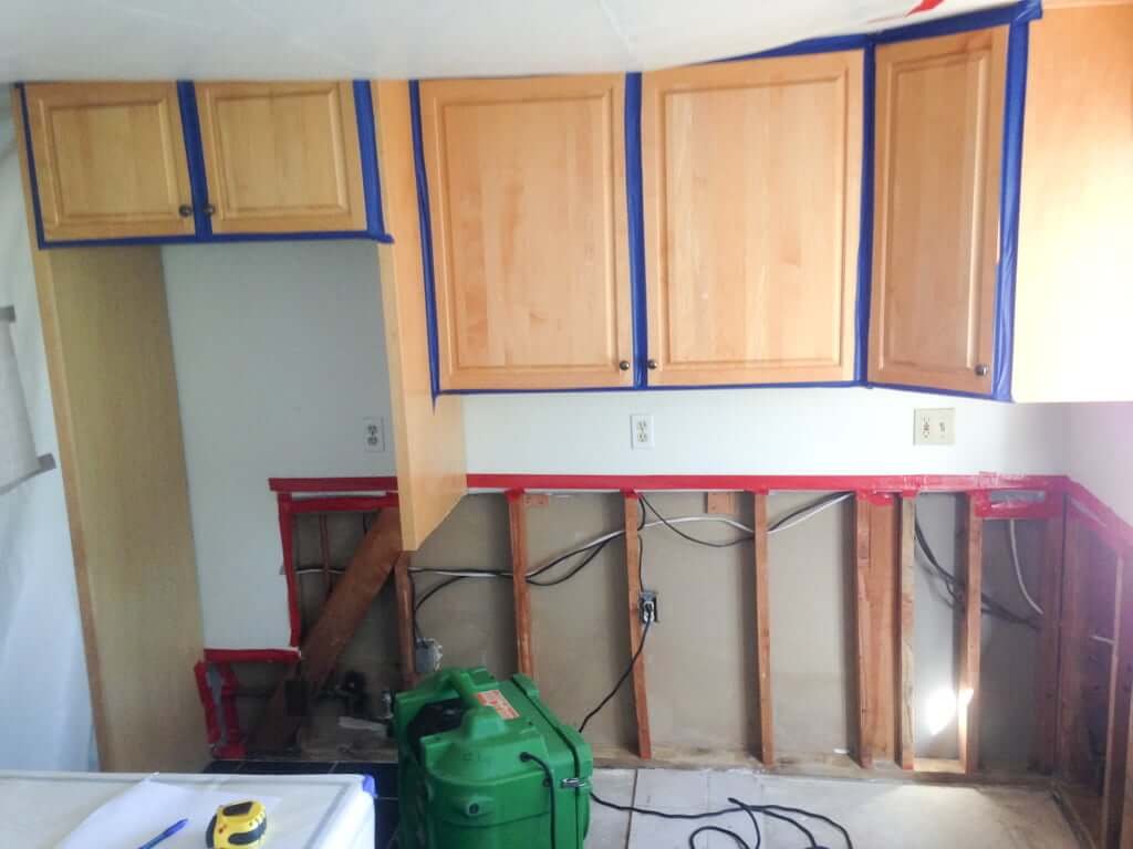 Kitchen upper cabinets taped up with lower cabinets removed