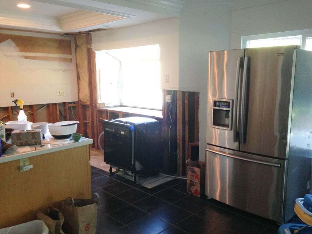 refrigerator and dishwasher in kitchen with all cabinets removed and drywall removed.