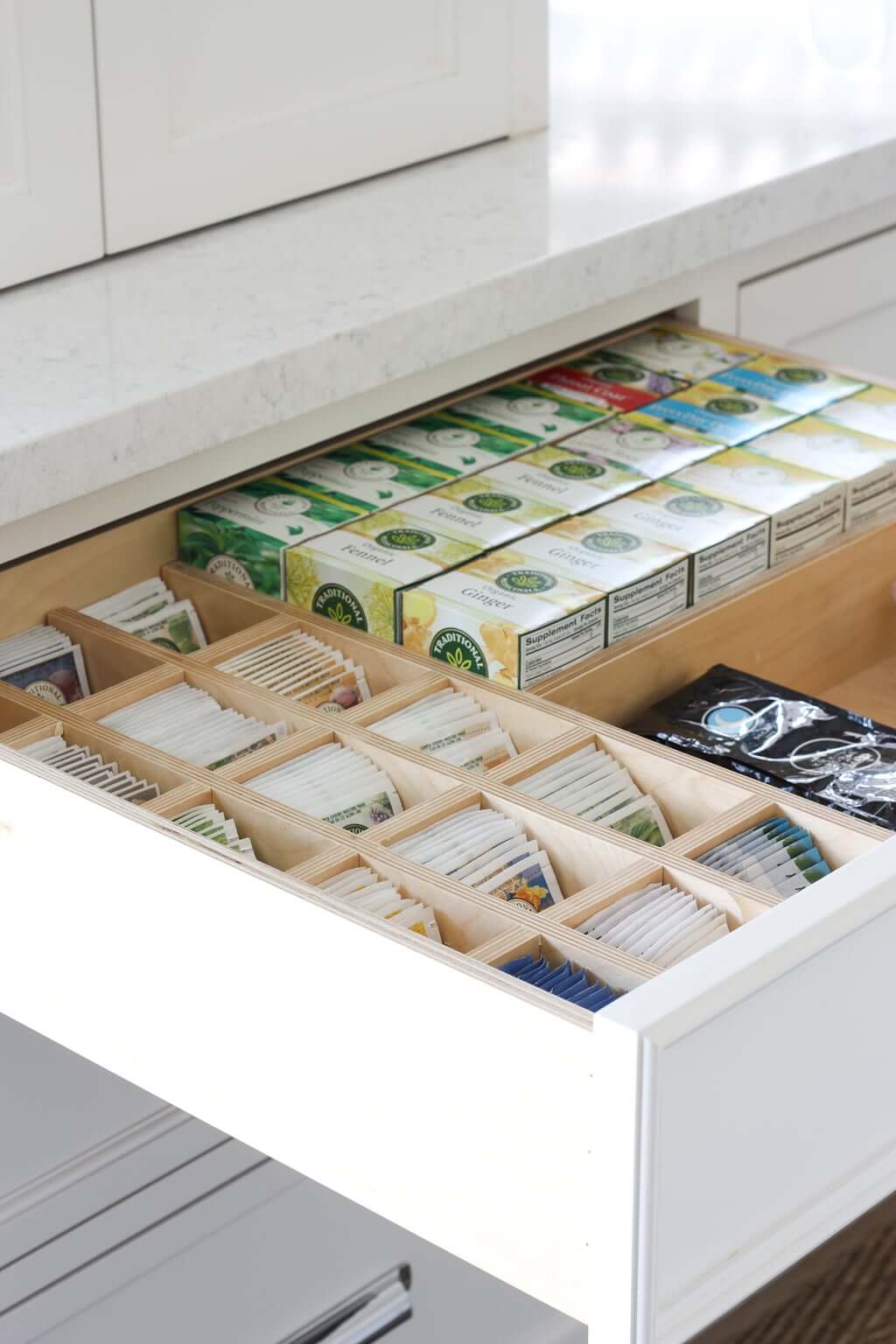 An open drawer in a kitchen showcases how to organize tea with drawer dividers