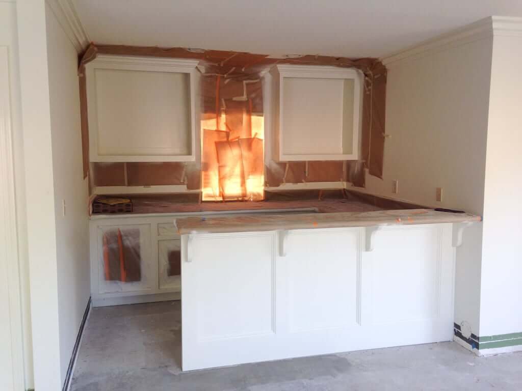 bar area with cabinets painted white, paper still taped up