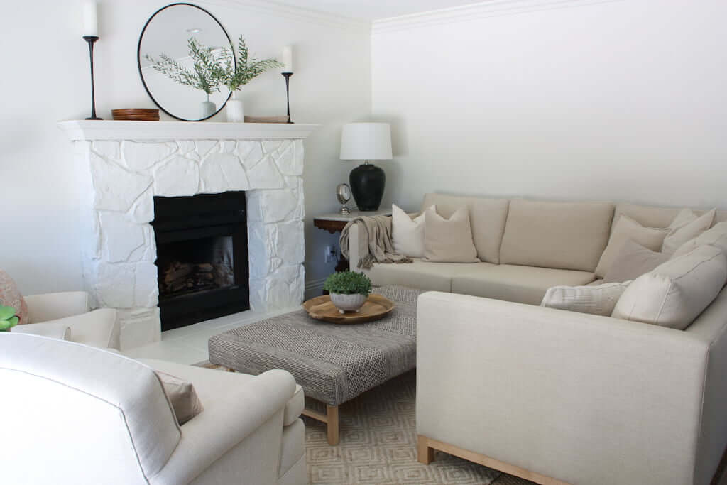 neutral living room with sectional and white stone fireplace