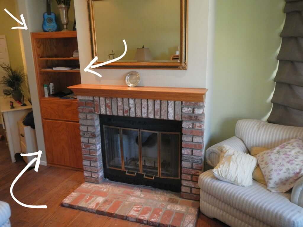 arrows pointing to oak built in bookshelves and drawer next to a brick fireplace with armchair