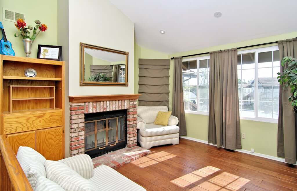 sitting room with fireplace, built in wood bookcase, loveseat and armchair in front of windows