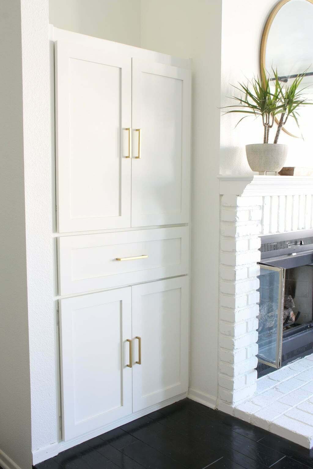 white built-in bookcase, cabinets, and drawer next to fireplace