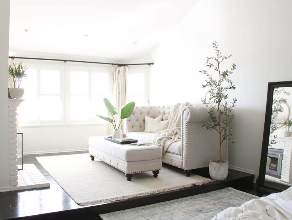 master bedroom with separate sitting area with couch, ottoman and fireplace