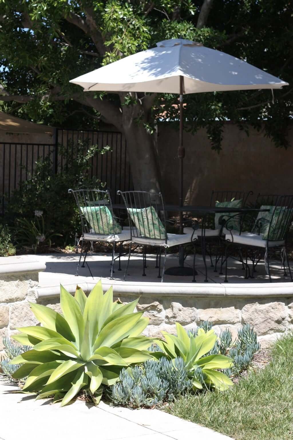 raised patio with stone veneer retaining wall, outdoor dining area and umbrella on patio