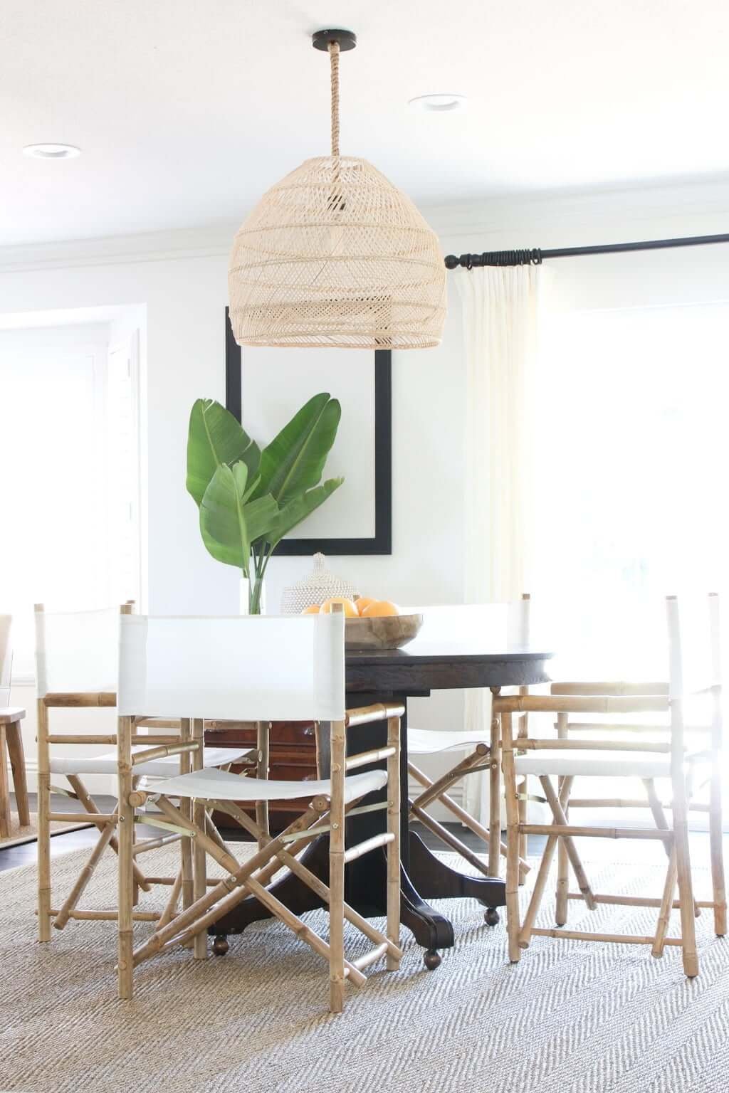 dining room with round wood table, directors chairs, seagrass rug and woven pendant